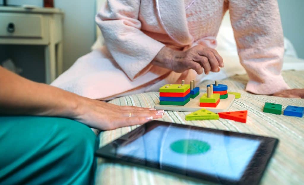home help showing geometric shapes to elderly memory care patient