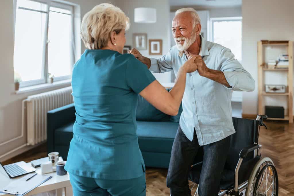 caregiver in a home assisting senior man to get up