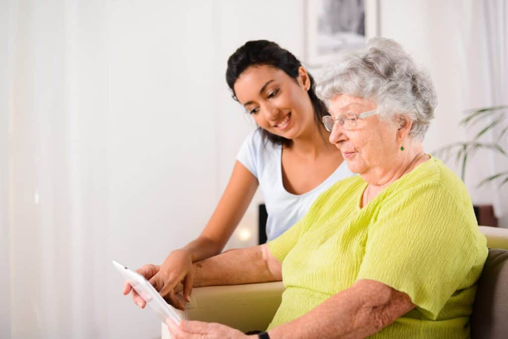 nursing home assisted living. Cheerful caregiver helping a senior woman with her digital tablet.