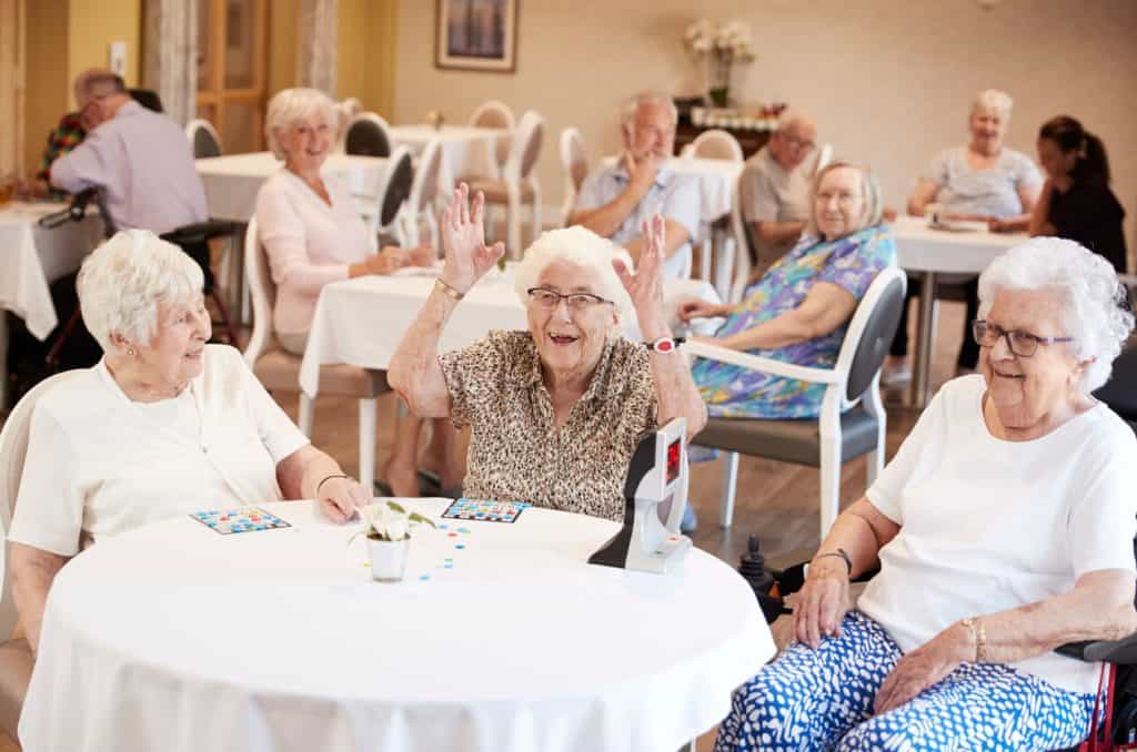 senior women playing game of bingo happily in a low income assisted living facility
