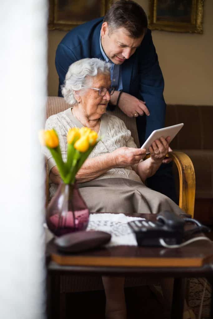 Son showing his mother a digital tablet in an assisted living home
