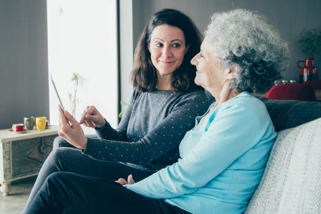 what is assisted living? An adult woman with her senior mom using a tablet