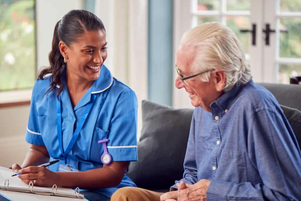 Eldery man at home laughing and talking with a female caregiver jobs