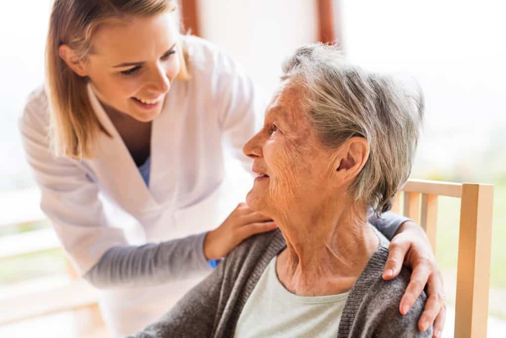 Caregiver talking to a senior woman at home, caregiver jobs