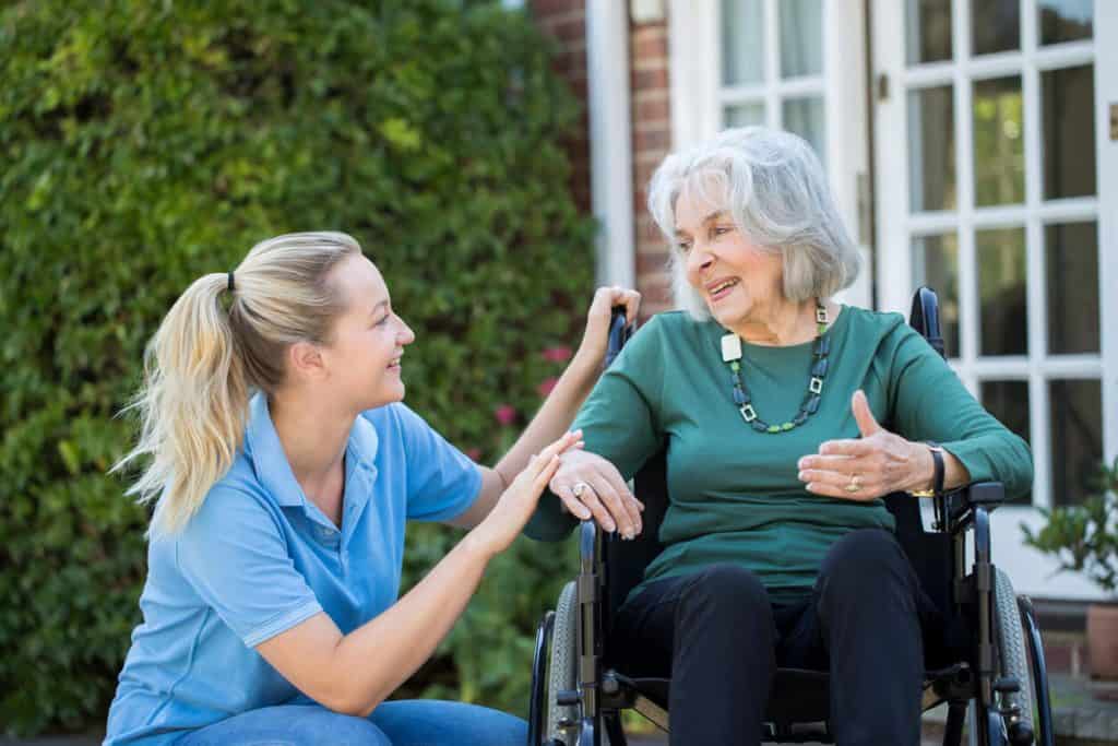 private live in caregiver jobs near me A live-in caregiver is smiling to a senior woman in a wheelchair.