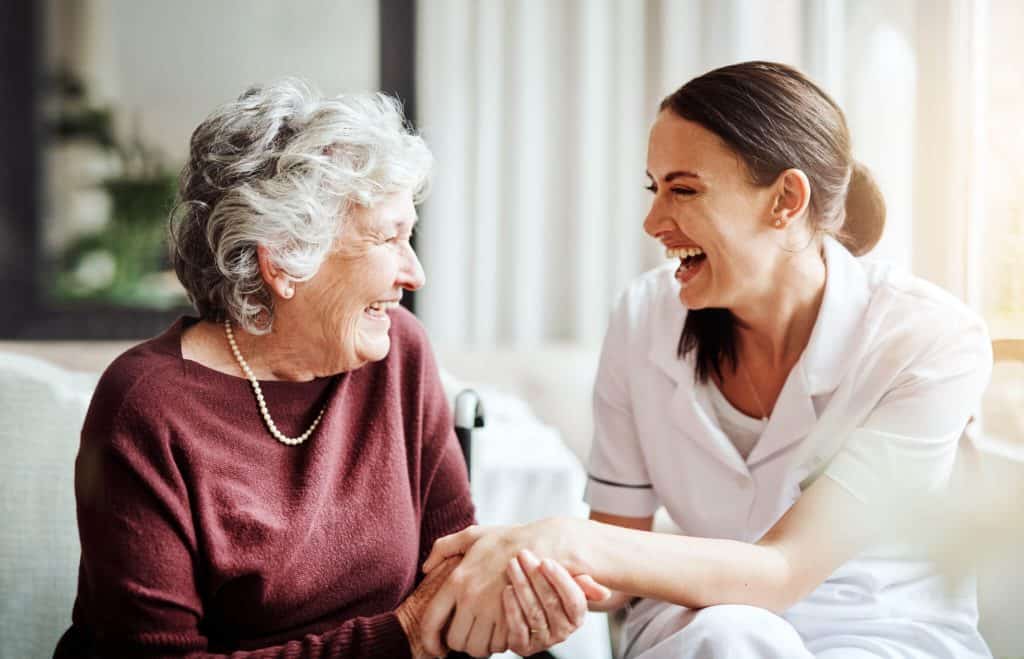 Senior woman bonding with caregiver at her home