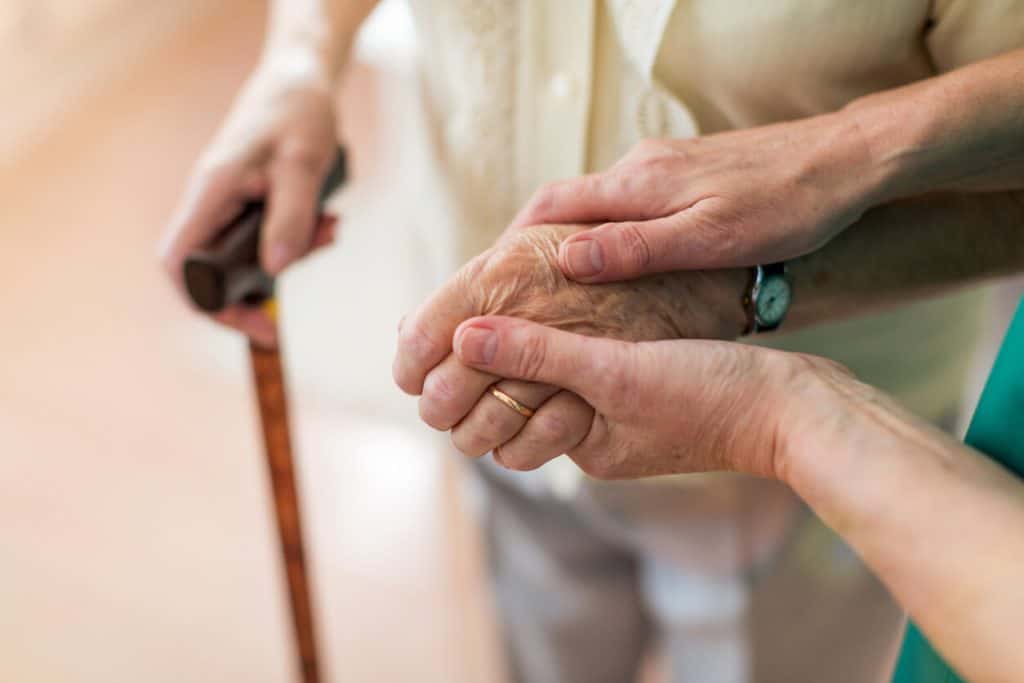Home care provider holding the hand of a senior 2022