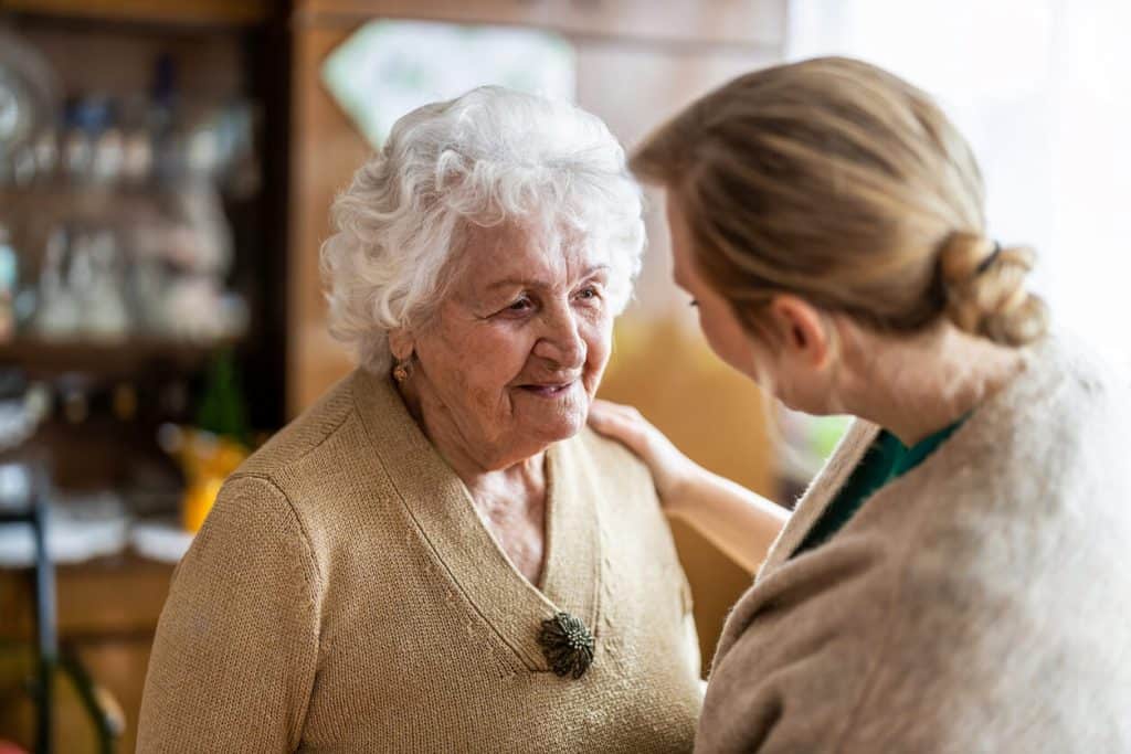 Mental health assisted living, caregiver patiently talking to an elderly woman.
