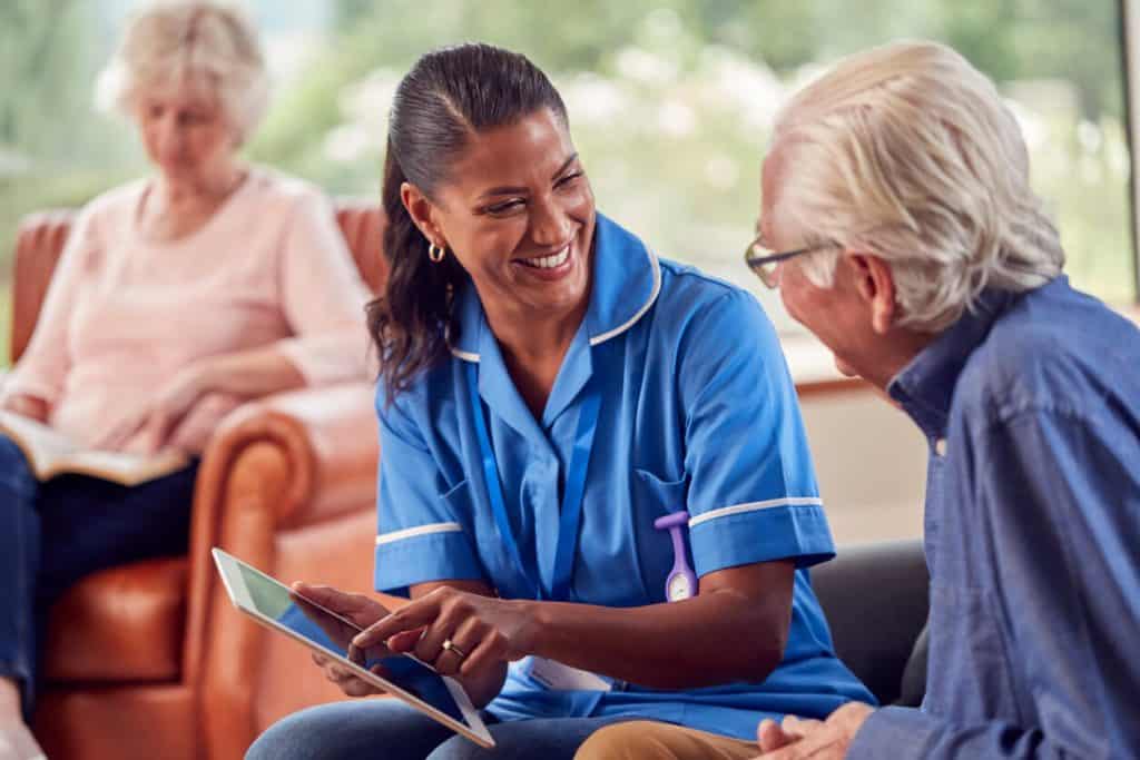 A nursing assistant helping an elderly couple, in home care for seniors jobs