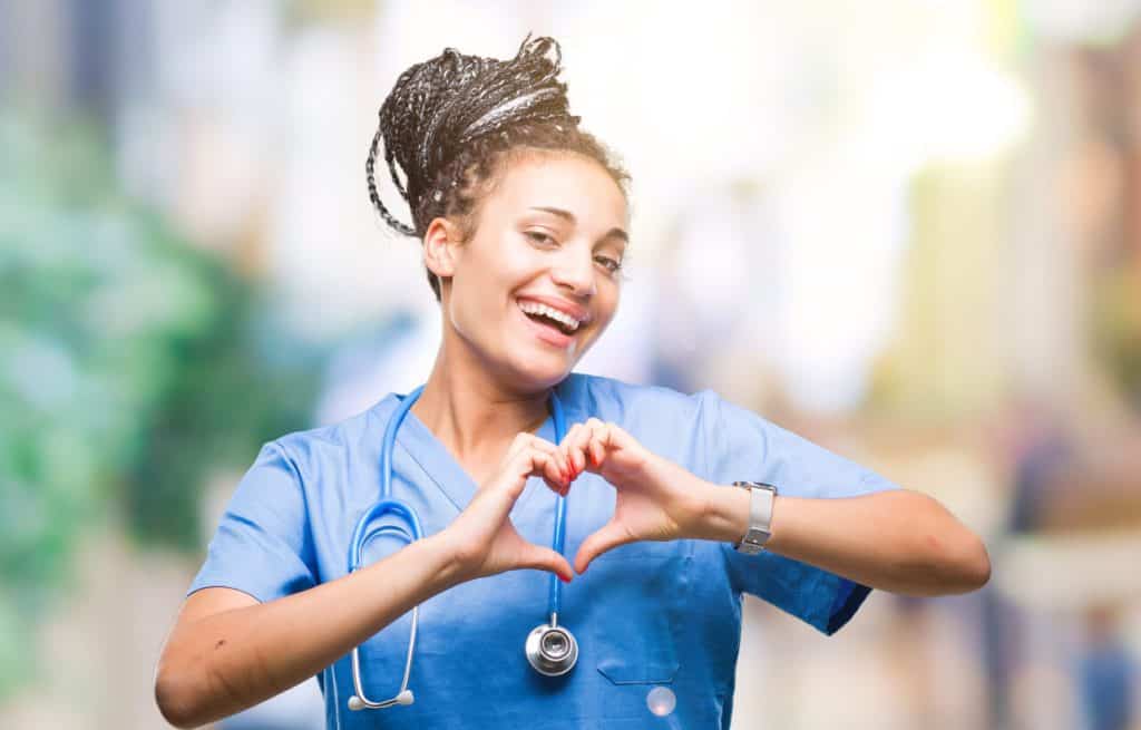 Smiling, happy young female caregiver making a heart with her hands, caregiver work