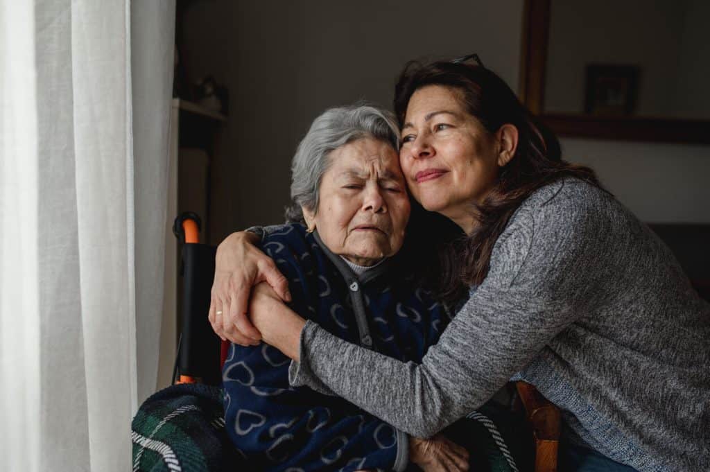 middle-aged daughter caregiver hugging her mom in a wheelchair, what is home health care