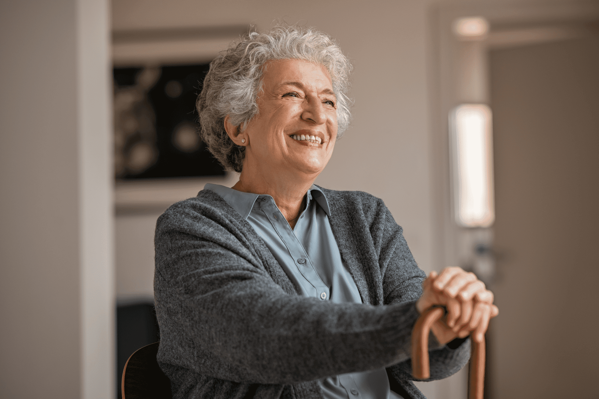 Senior woman with a cane enjoys sitting in the comfort of her own home