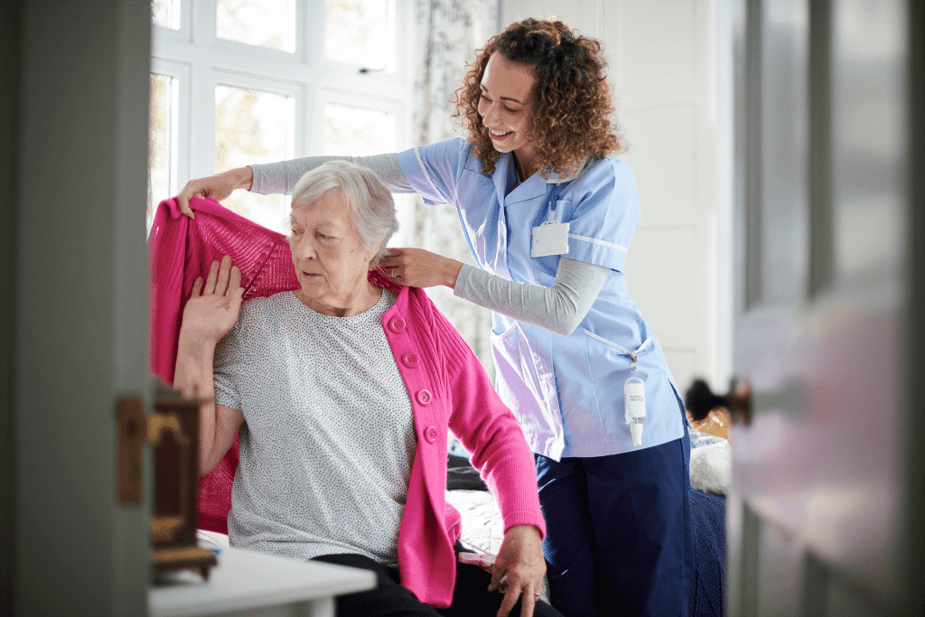 Home nurse care helping older woman get dressed