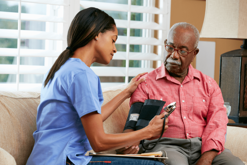 Female in-home nurse measuring blood pressure of an elderly man, home care nursing
