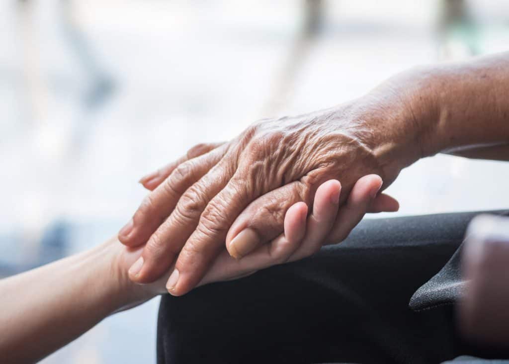 Elderly person holding hands providing care with home nursing services caregiver