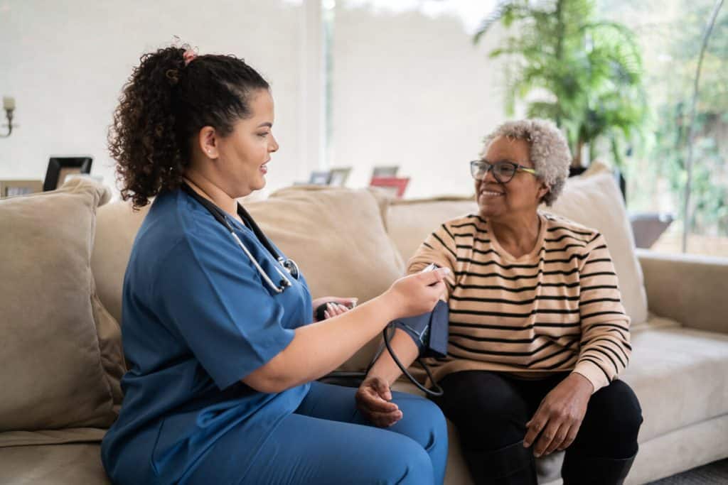 personal care nurse taking senior blood pressure in the comfort of their own home 2023, in home nursing care