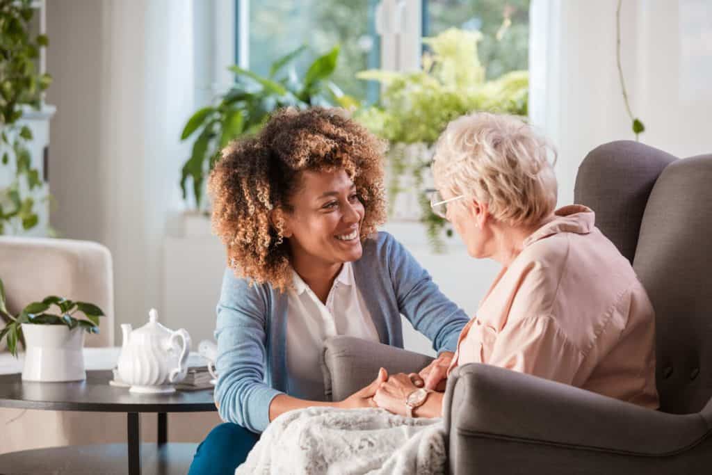 Female caregiver supporting an elderly lady in the privacy of her home, care in homes caregivers