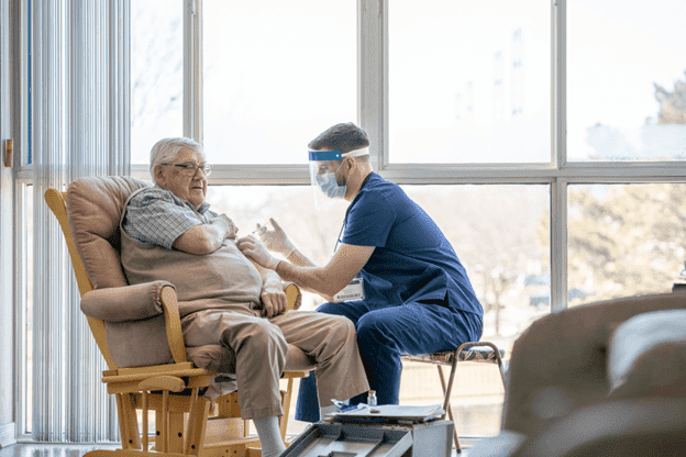 Male nurse administering injection to an elderly man at in home nursing