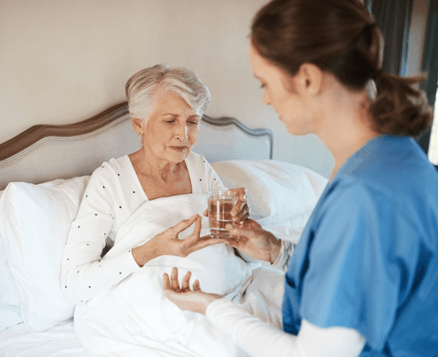 Home nurse giving medication to the elderly woman in home nursing 2022