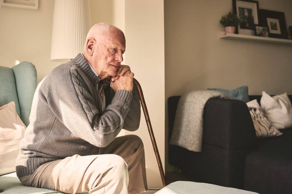 Elderly man looking sad sitting on his bed alone at home, assistance home care