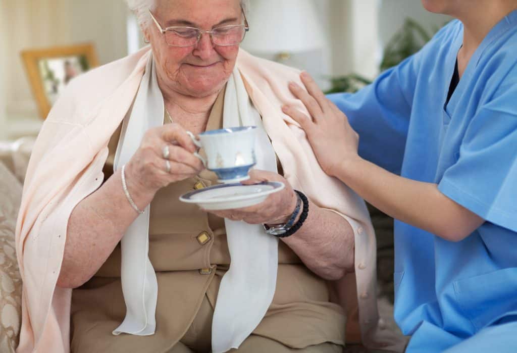 nonmedical home care worker helping an elderly woman drink tea 2023. non medical home care agencies