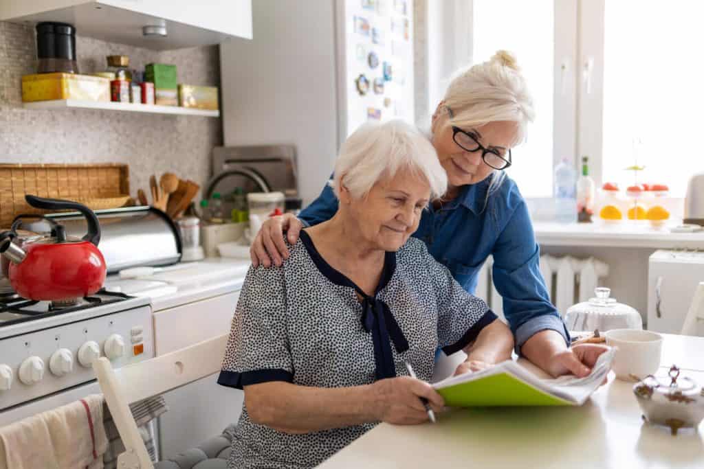 Caregiver reading letter with elderly mother from pen pals for seniors 2022