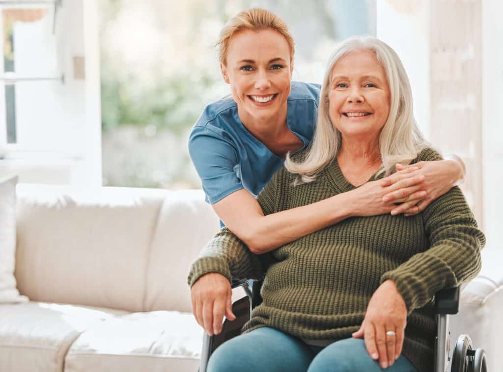 female caregiver happily hugging the senior she sits with. sitters for the elderly jobs