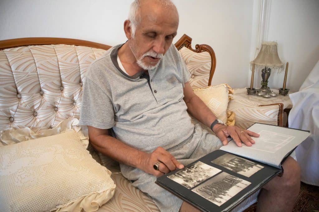 senior man looking through a family photo album to make connection 2022 2023. sitters for the elderly jobs