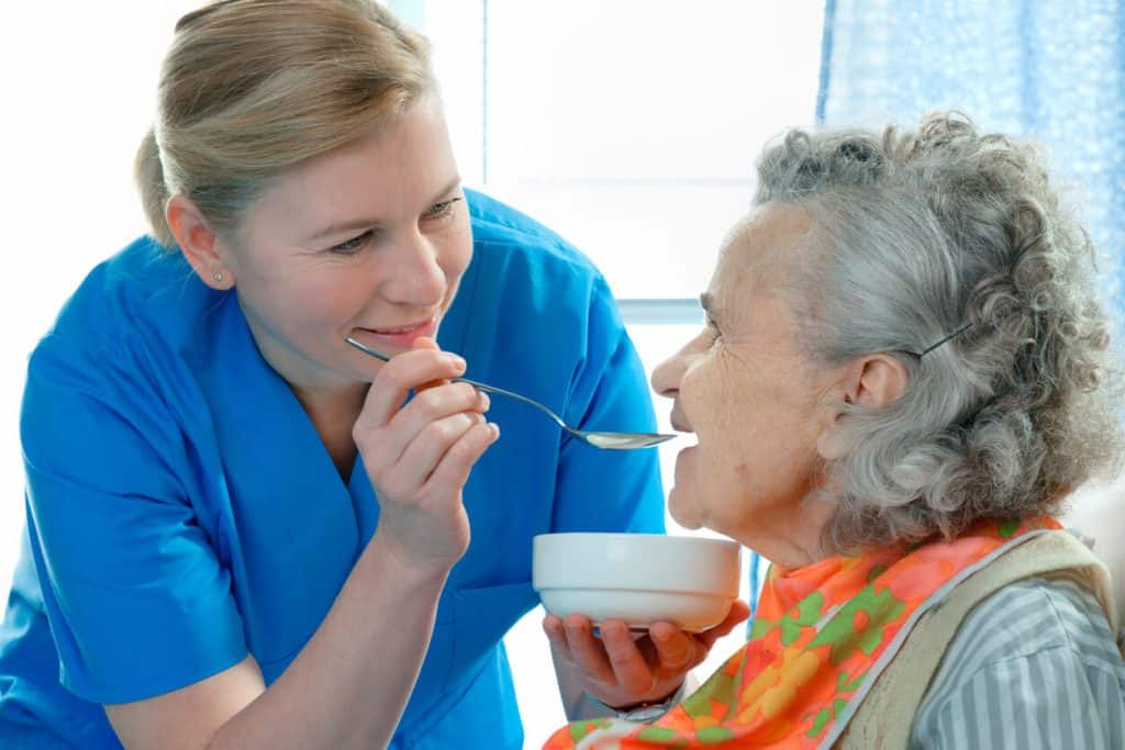 caregiver feeding a senior woman, caregiver careers 2023 site. 24 hour nursing care at home
