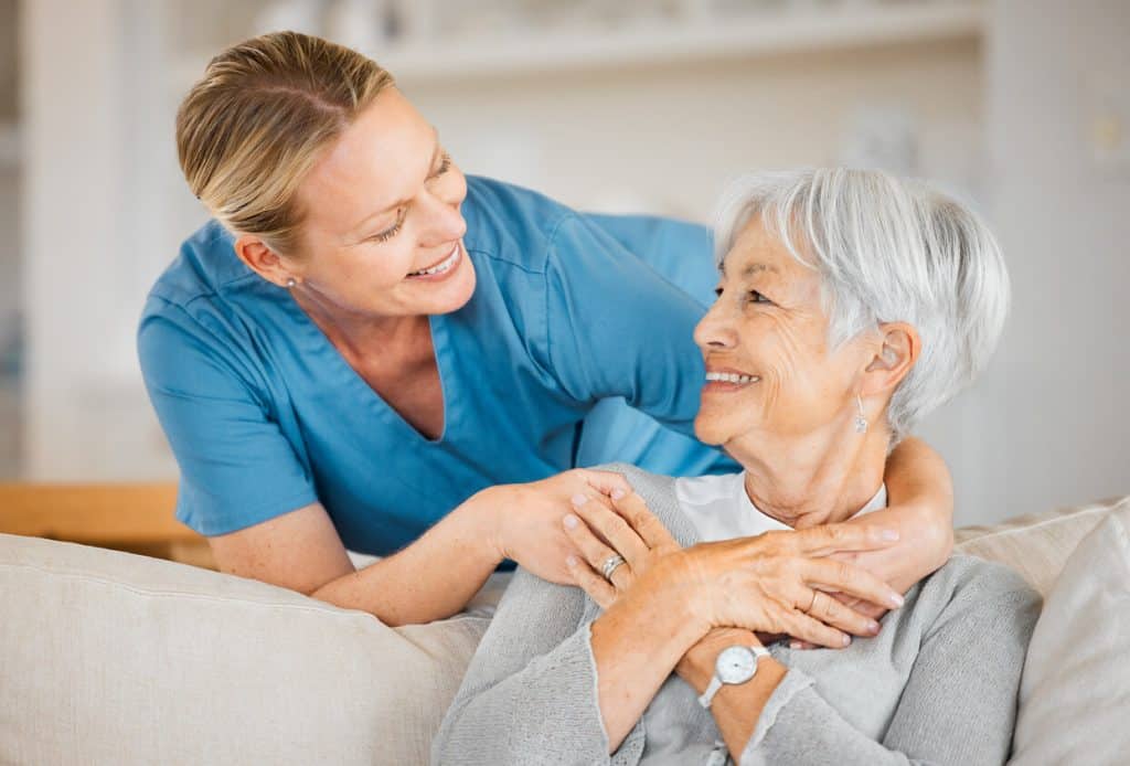 how to become a caregiver, caregiver requirements- female nurse caring for an elderly woman at home