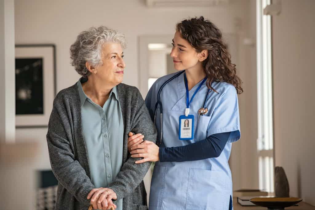 a young caregiver assisting an older woman after taking a home care course online