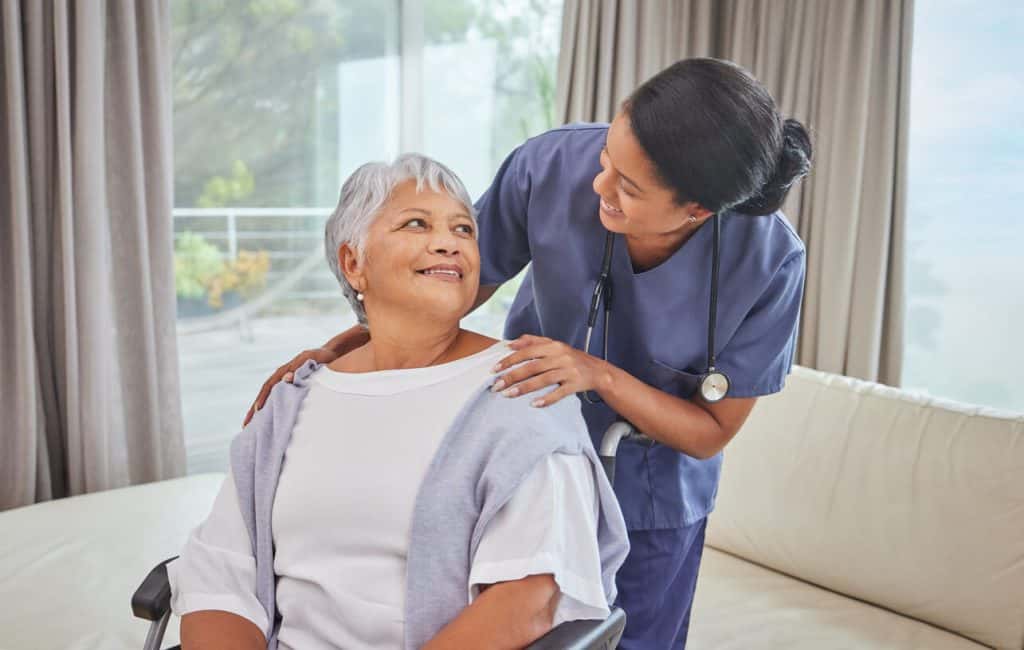 Young female trained caregiver smiling at an older woman in her home. caregiver training institute