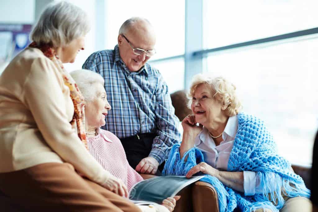 A group of four seniors chatting happily about unique activities for seniors