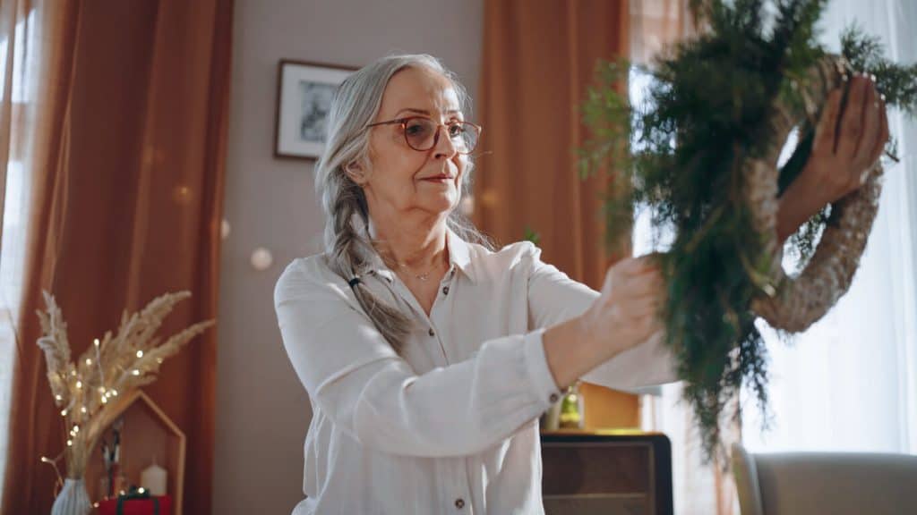 A senior woman holding a Christmas wreath she made. unique activities for seniors