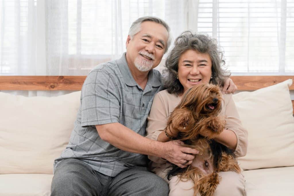 A happy senior couple sitting and petting their dog. unique activities for seniors