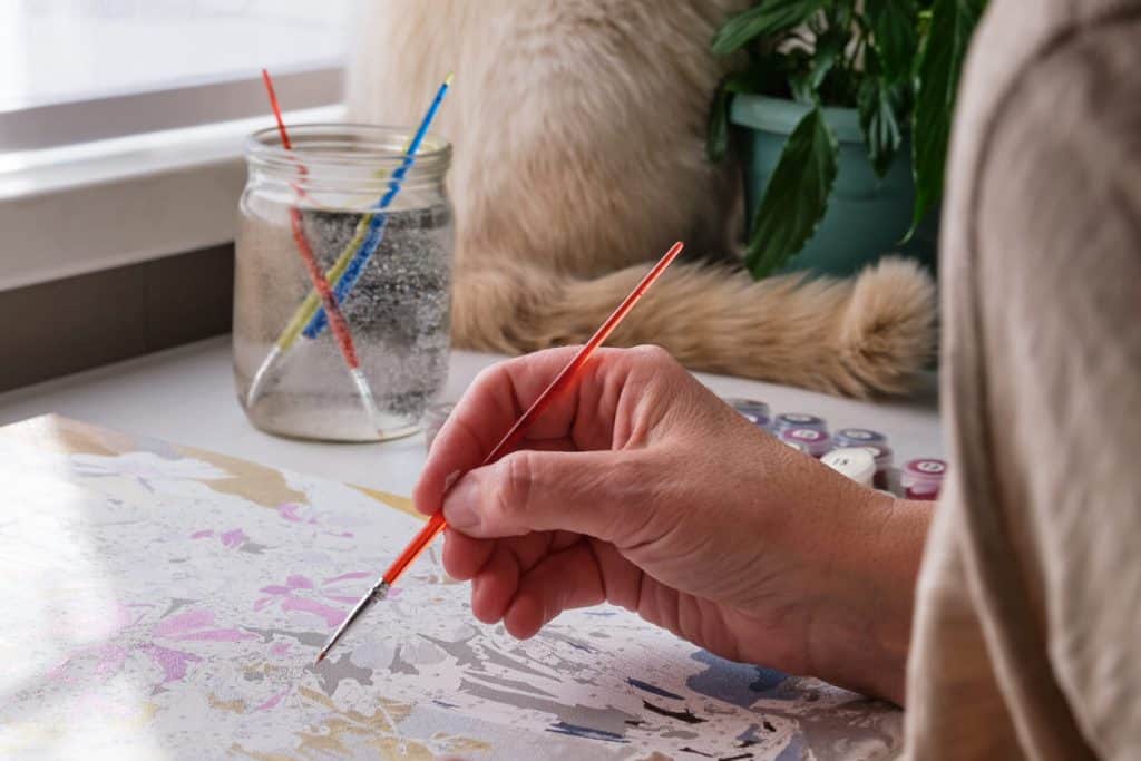 An older woman holding a brush and painting. unique activities for seniors