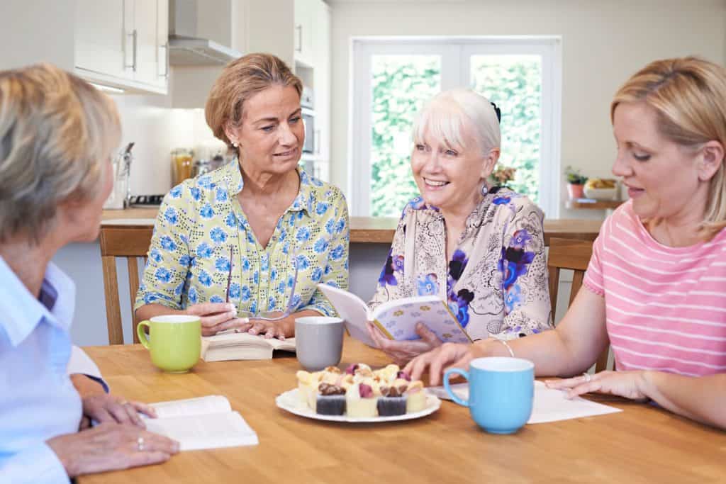 A group of three senior women and one younger woman meeting for a book club. unique activities for seniors