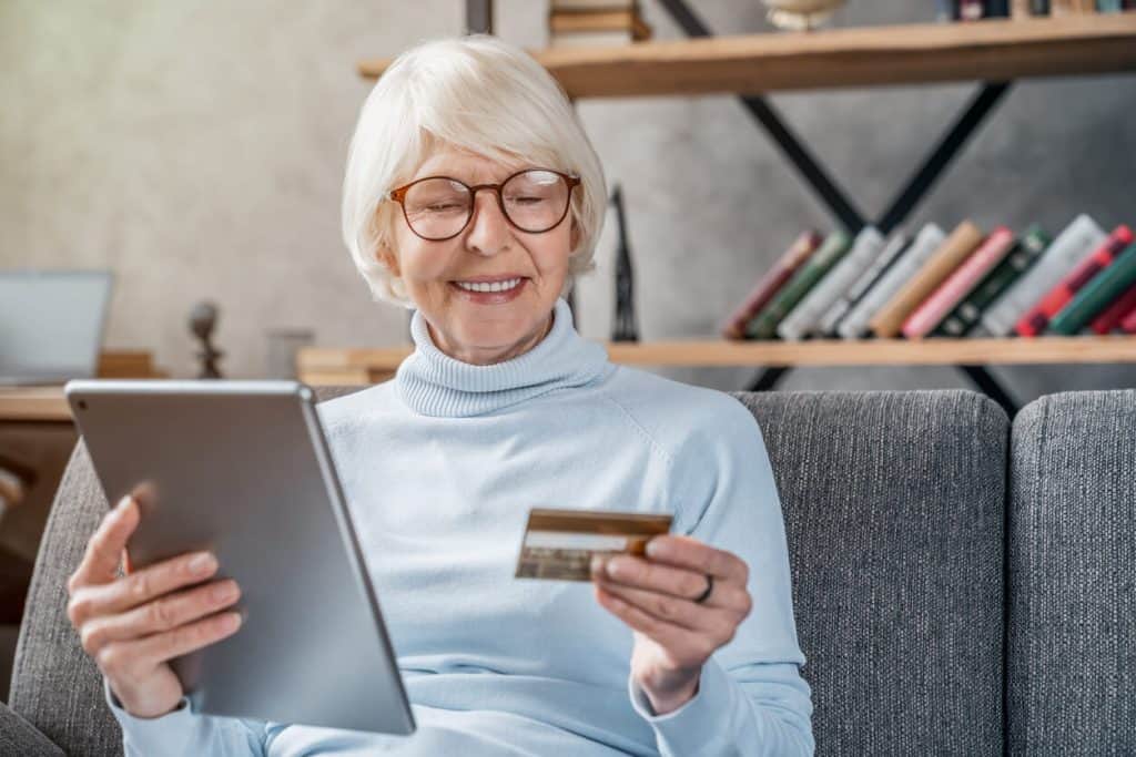 A senior woman holding a credit card and using a tablet to shop online. unique activities for seniors