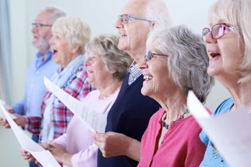 A group of six seniors singing in a choir. unique activities for seniors