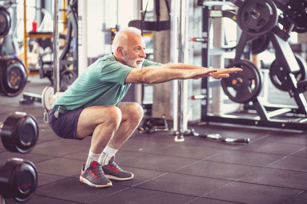 A senior man doing squats at the gym. unique activities for seniors