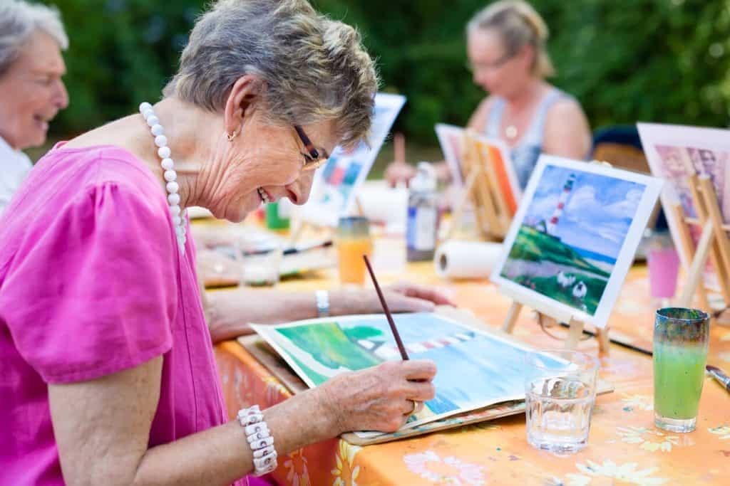 An older woman smiling while drawing, activities for seniors in nursing home