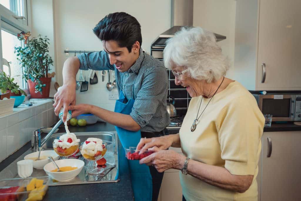 An older woman helping her caregiver in baking in an assisted living home, activities for seniors in elderly homes to keep them active