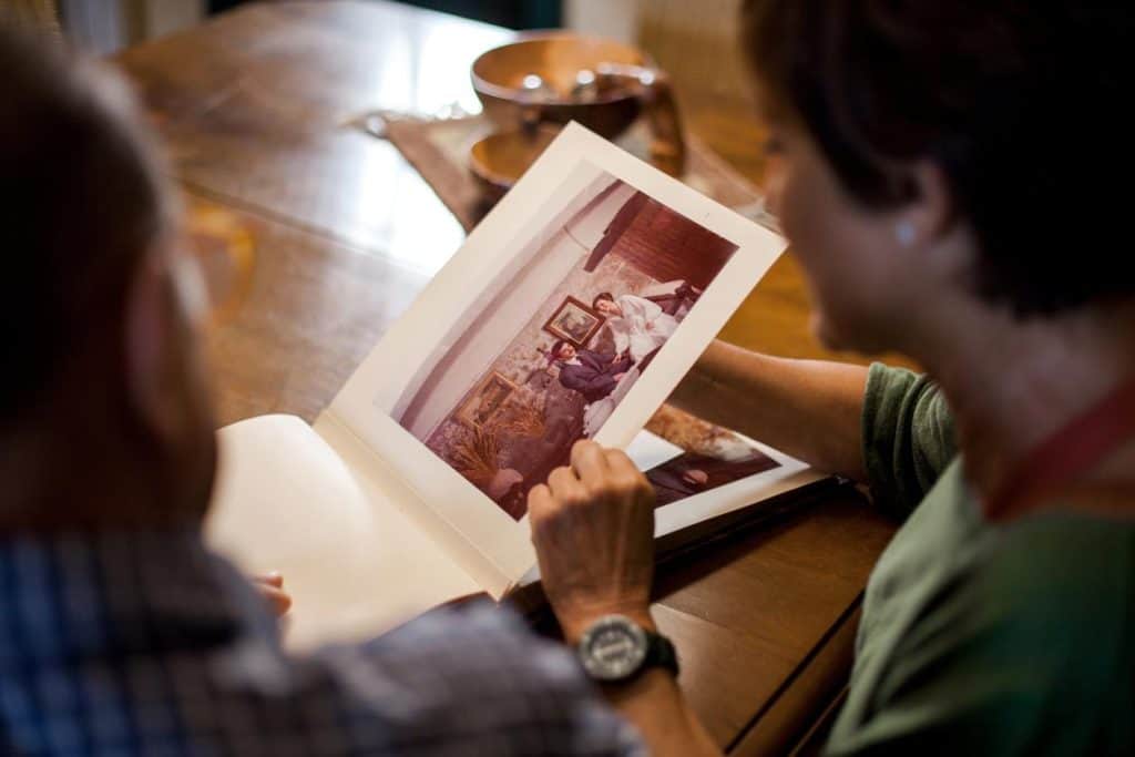 An older man sharing looking at his wedding photo album with his caregiver, activities for seniors in long term care facilities