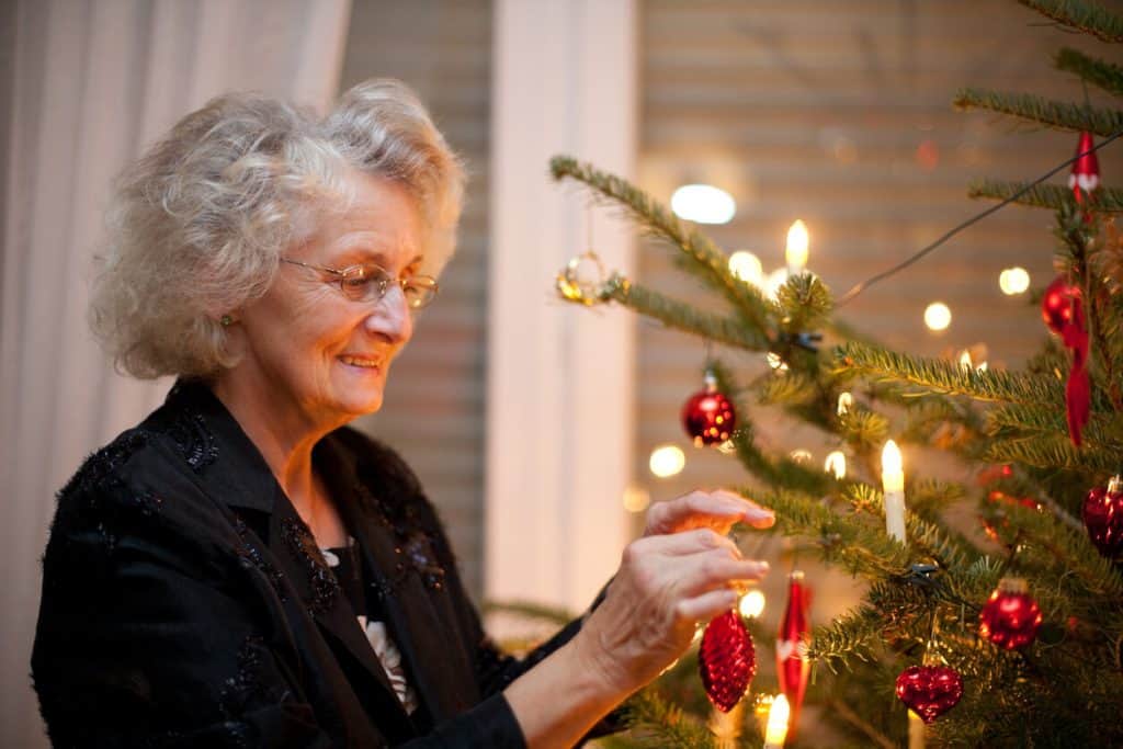 A senior woman decorating the Christmas tree in the nursing home, fun activities for seniors in assisted living