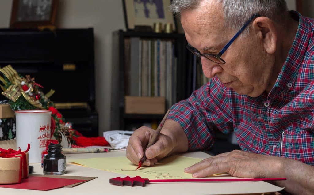 An older man writing Christmas card, activities for seniors in long term care facilities