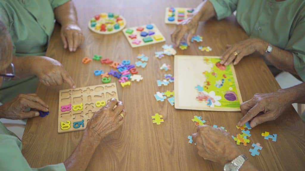 A group of older people playing puzzles, activities for seniors in retirement homes