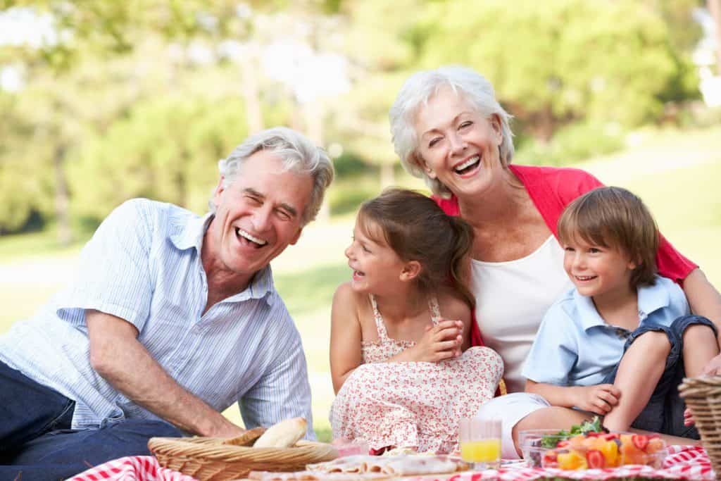 Older couple enjoying picnic with their grand children, assisted living activities for seniors