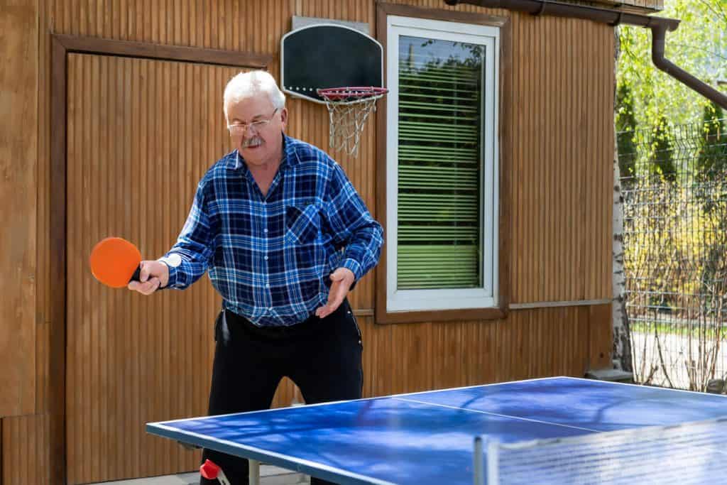 An elderly man playing ping pong, activities for seniors that love sports in assisted living