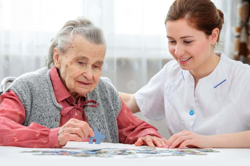 indoor activities for seniors - senior woman with her caregiving solving a puzzle