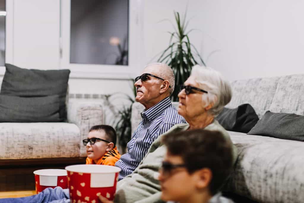 Senior watching movie at home with family - indoor activity for seniors